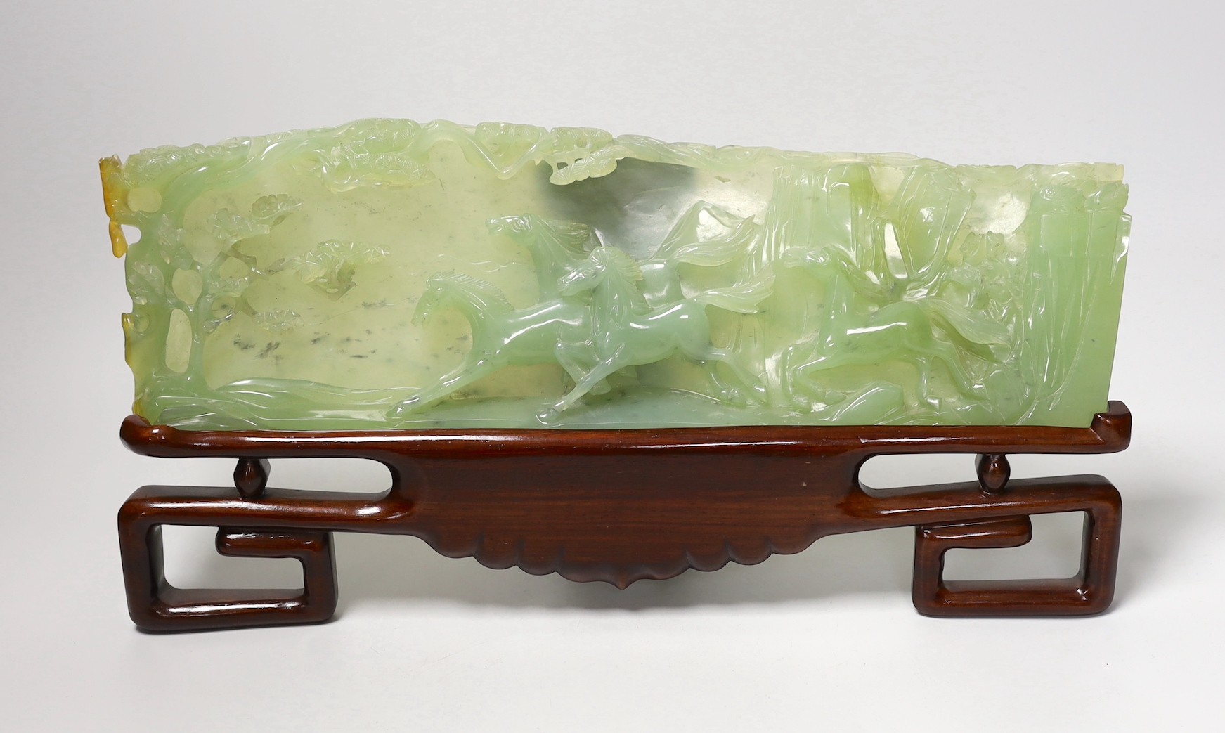 A large Chinese bowenite jade plaque of galloping horses, wood stand, 40cm wide